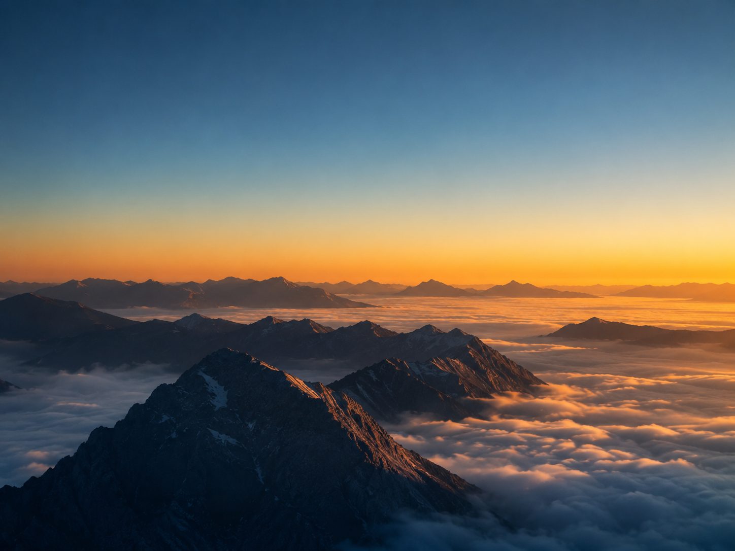 A mountain ridge rising above a sea of clouds at sunrise